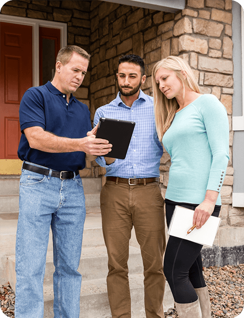 Home inspector reviewing findings on a tablet with clients on-site